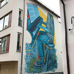 Ein Graffiti von Streetartkünstler Daniel Schuster (Daschu) an einer Biberacher Hauswand zeigt ein Klavier spielendes Kind in geringeltem T-Shirt, Jeans und Turnschuhen.