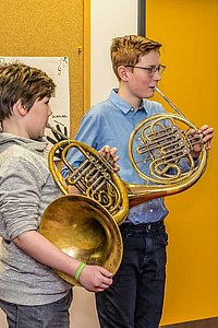 Musiklehrerin und zwei jugendliche Schüler spielen gemeinsam Horn 