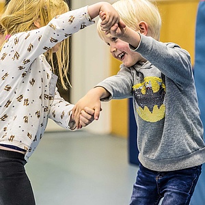 Zwei Vorschulkinder halten sich an den Händen und tanzen fröhlich miteinander