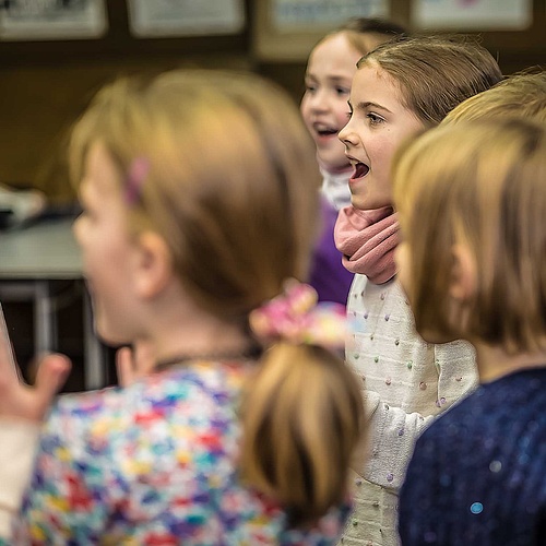 Grundschulkinder stehen im Kreis und singen und klatschen im Chor