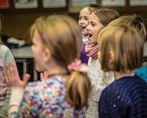 Grundschulkinder stehen im Kreis und singen und klatschen im Chor